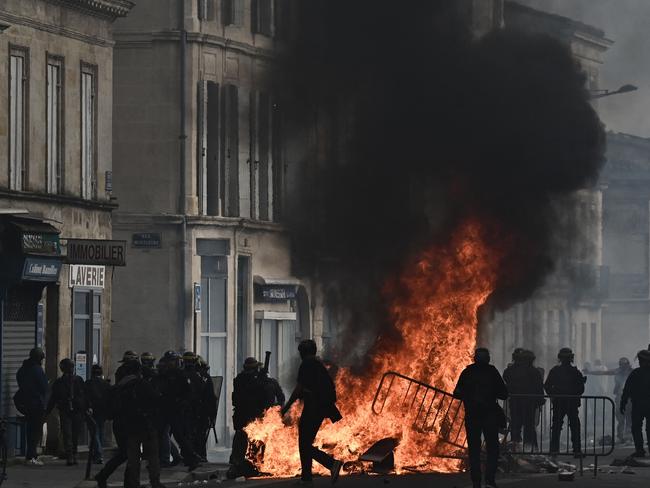 Anti-riot police officers stand guard next to a fire set by protesters during a demonstration on a national action day in Bordeaux. Picture: AFP