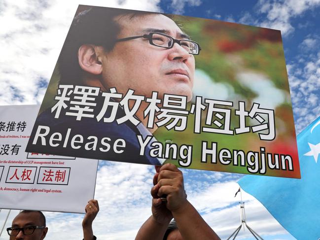 Protesters hold placards demanding the release of writer and businessman Yang Hengjun during a rally organised by the Alliance for Victims of the Chinese Communist Regime outside Parliament House in Canberra on March 20, 2024. China's Foreign Minister Wang Yi began a whirlwind visit to Australia on March 20, his rare trip marking a thaw in relations between the two trading partners. (Photo by DAVID GRAY / AFP)