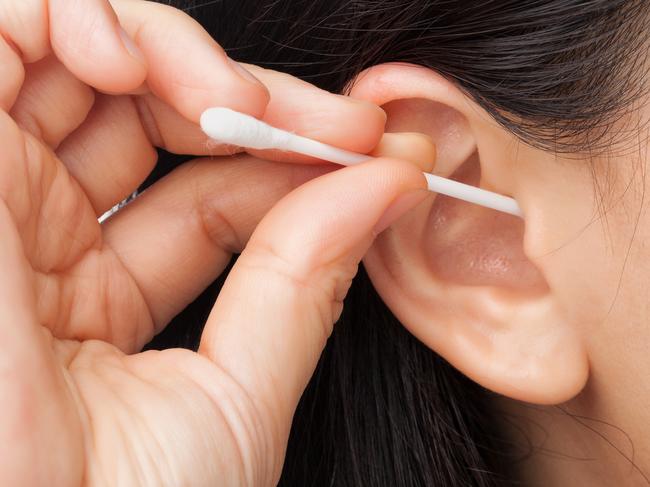 Woman cleaning ear using cotton stick