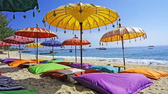 This image shows some colourful beach umbrellas and sand pillows in a pristine tropical beach bathed by the Bali sea.Escape 2 June 2024Kendall HillPhoto - iStock