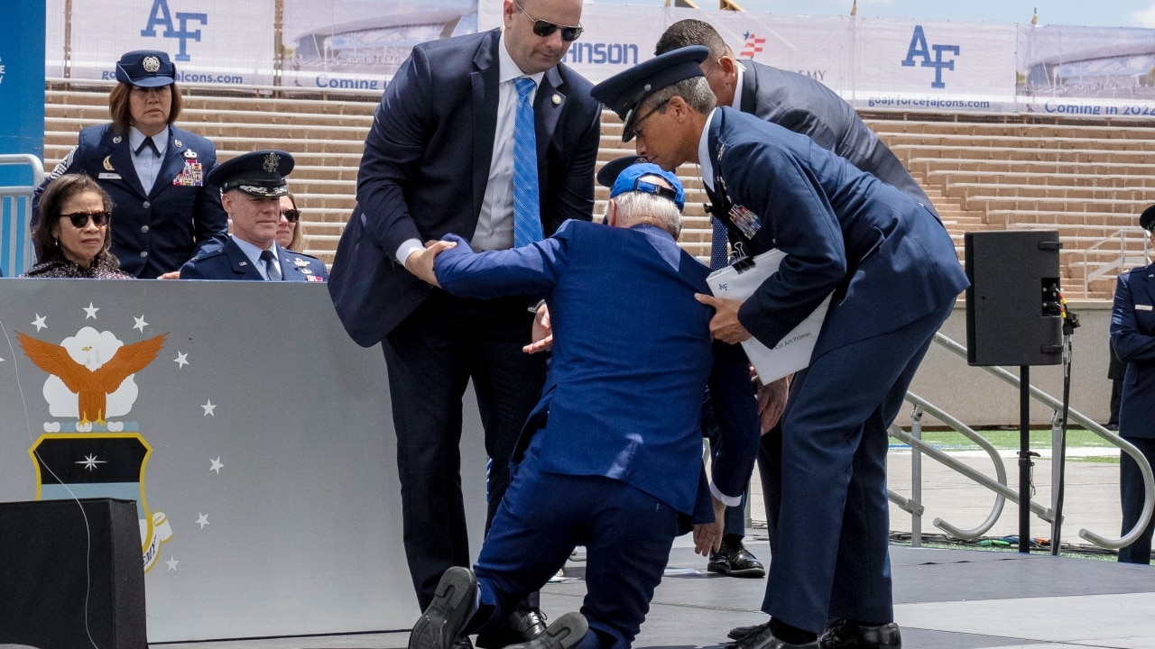 Aiuta il presidente degli Stati Uniti Joe Biden a rimettersi in piedi dopo essere inciampato e caduto sul palco durante un evento ufficiale alla US Air Force Academy