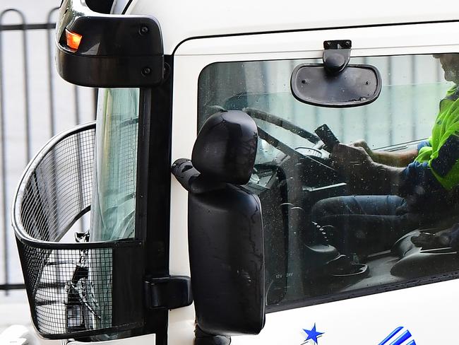 A truckie holds his phone on South Rd while driving under Black Forest tram stop on Thursday. picture: AAP / Mark Brake