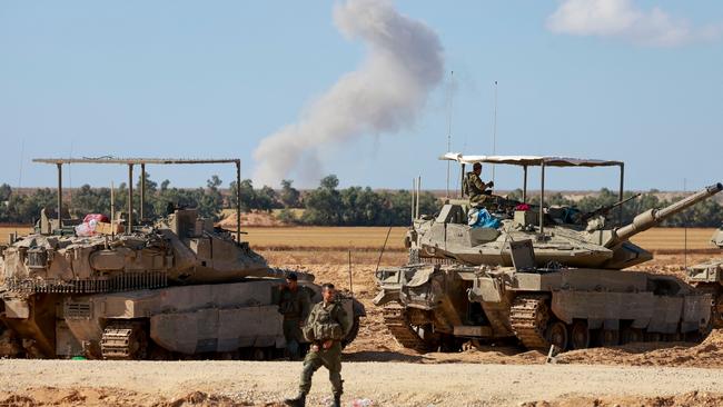 Israeli tanks take position in southern Israel near the border with the Gaza Strip as smoke billows over Gaza during Israeli bombardment on Monday. Picture: AFP