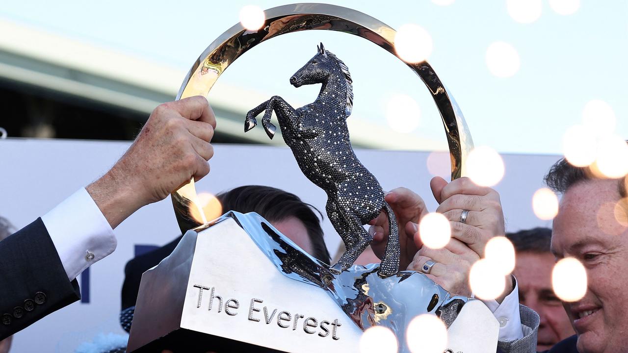 Team members of Australian sprinter, Think About It, lift the winning trophy after the world's richest turf race, The Everest, in Sydney on October 14, 2023. (Photo by DAVID GRAY / AFP)