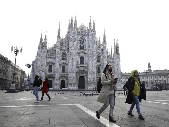 A woman wearing a sanitary mask walks past the Duomo gothic cathedral in Milan. The Lombardy region is set to go into lockdown. Picture: AP