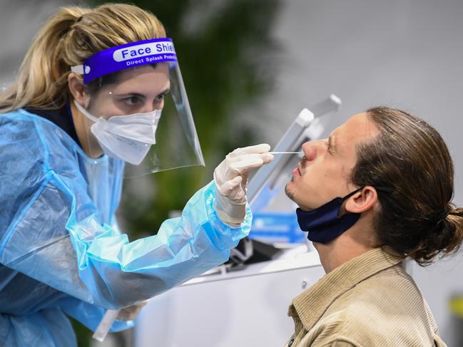 SYDNEY, AUSTRALIA - NOVEMBER 23: A passenger has their throat and nose swabbed for COVID-19 inside a pre-departure testing clinic outside the departures hall at Sydney Airport on November 23, 2021 in Sydney, Australia. A new COVID-19 testing clinic currently capable of 4000 tests per day has opened at Sydney Airport to provide international travellers rapid testing within 90 minutes for a fee of $79.00 Australian dollars. Australia's COVID-19 border restrictions were lifted on 1 November to allow people to travel overseas without government exemption, with most airlines and countries now requiring proof of a negative COVID-19 test within 72 hours of departure. (Photo by James D. Morgan/Getty Images)