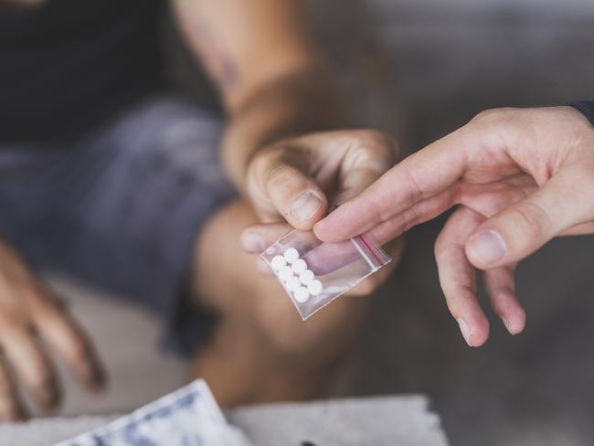 Drug dealer selling ecstasy pills to a drug addict