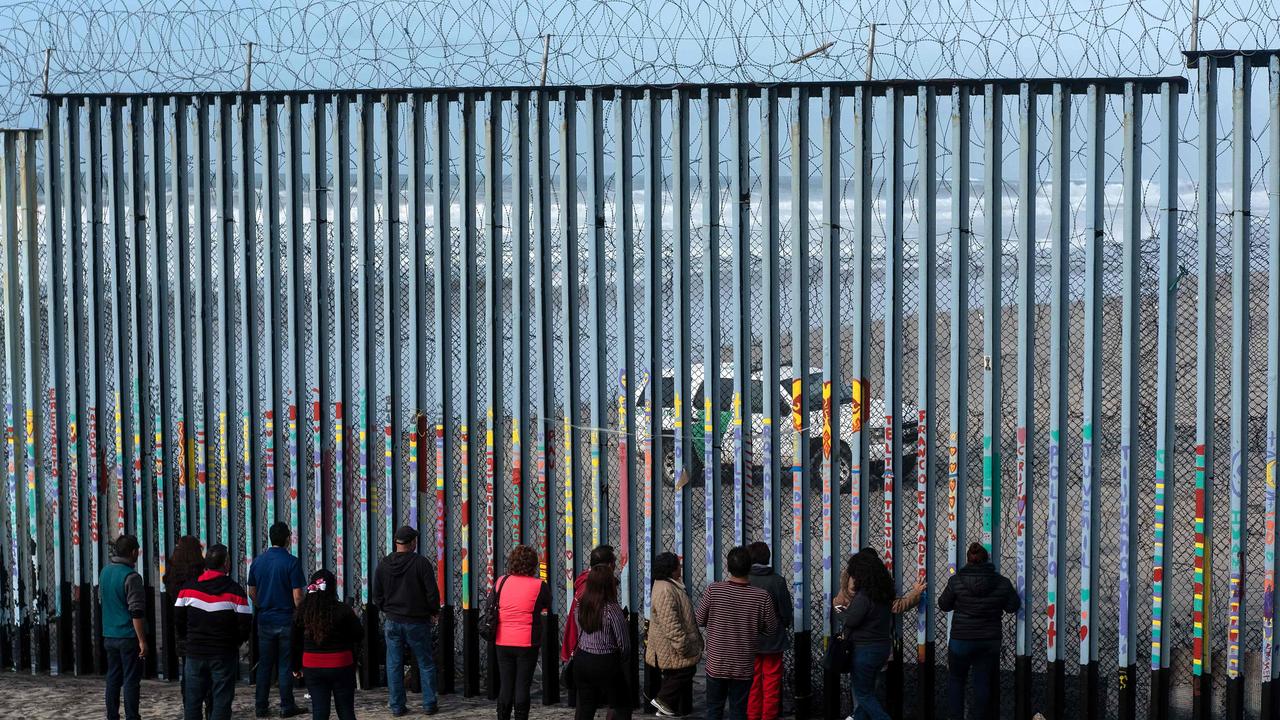 People look at US border patrol guards through the US-Mexico border fence in Tijuana, Mexico, on January 18. Picture: Guillermo Arias/AFP