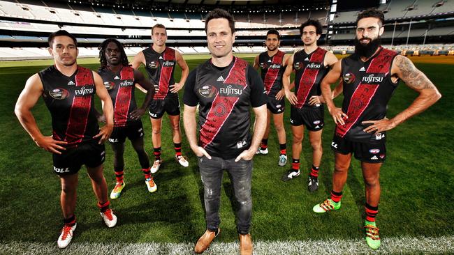 Essendon champion Gavin Wanganeen, pictured with Bombers’ indigenous players Matthew Stokes, Anthony McDonald-Tipungwuti, Shaun Edwards, Yestin Eades, Jake Long and Courtenay Dempsey, models the guernsey he designed for the Dreamtime at the G’. Picture: Michael Klein