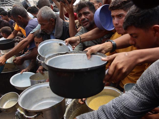 Palestinians push their way in front of a hot meal distribution point at a displacement camp near Gaza City's port on May 22, 2025. The Israeli army issued an evacuation warning on May 22 for 14 neighbourhoods of northern Gaza, as it pressed a renewed offensive that has drawn international condemnation. (Photo by Omar AL-QATTAA / AFP)