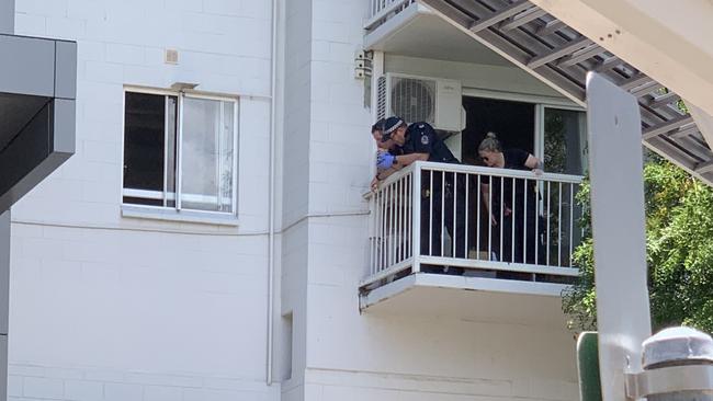 Police officers attempt to negotiate with the man after he climbed across two apartment balconies and into an alcove above the apartment block driveway. Picture: Sarah Matthews