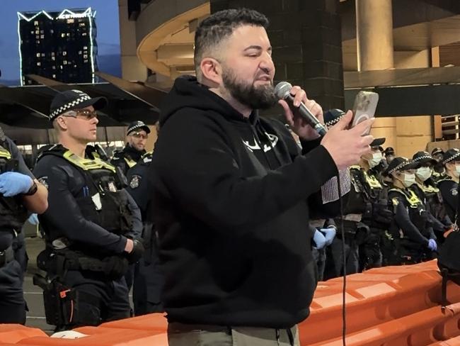 Burgertory boss Hash Tayeh addresses protesters in front of a wall of police on Thursday night.