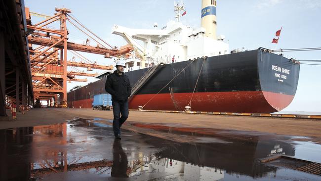 A man walks near a bulk carrier cargo ship docked at an iron-ore transfer and storage centre operated by the Shanghai International Port Group in Shanghai. Picture: Bloomberg