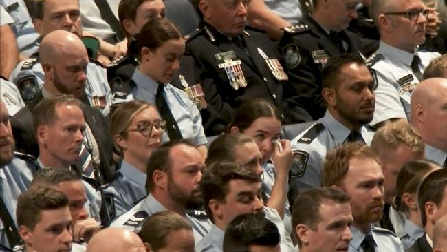 Surviving Constable Keely Brough (middle) wipes a tear during the memorial service.