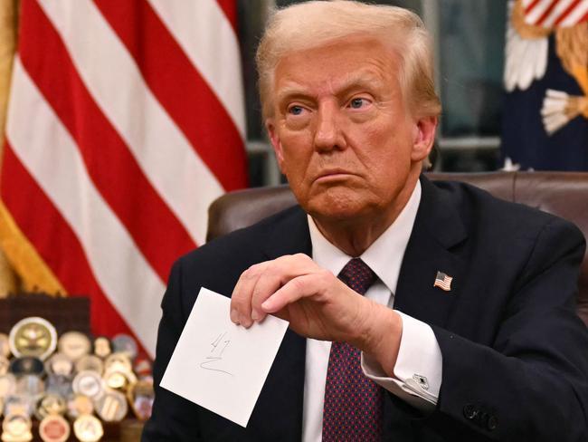 US President Donald Trump holds up outgoing President Joe Biden's letter as he signs executive orders in the Oval Office of the WHite House in Washington, DC, on January 20, 2025. (Photo by Jim WATSON / POOL / AFP) / ALTERNATE CROP