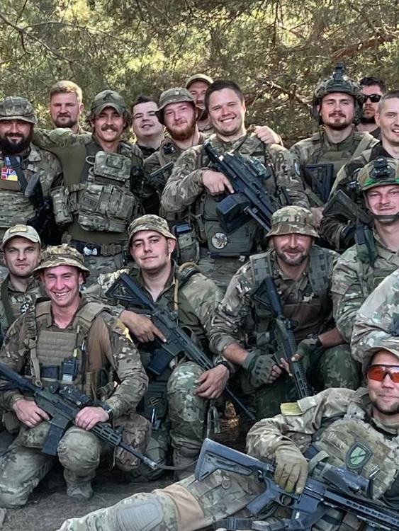 Felix Metrikas, third from left in back row, with Maks, a member of the Ukrainian National Guar, pictured centre with no hat holding a gun.