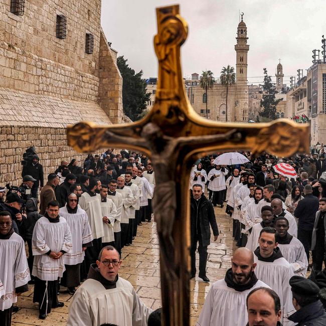 A crucifix is raised as deacons and other clergymen congregate for Christmas Eve celebrations outside the Church of the Nativity in the biblical city of Bethlehem.