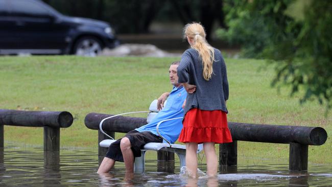 Elanora locals wait for the bus at a flooded Bus Stop on 19th Avenue. Photo: Scott Powick
