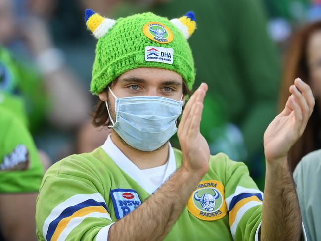 A Raiders fan wears a mask as he applauds a try during the Round One NRL match between Canberra Raiders and Gold Coast Titans at GIO Stadium in Canberra, Friday, March 13, 2020. (AAP Image/Lukas Coch) NO ARCHIVING, EDITORIAL USE ONLY