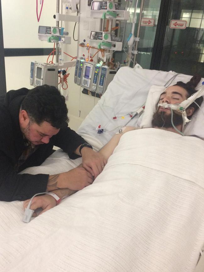 Dad Jon holds his son Jaiden's hand in ICU.