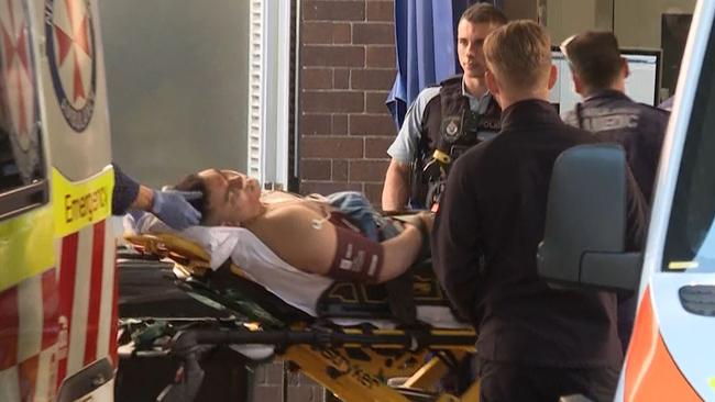 One of the shooting victims is watched over by police as paramedics work to save him. Picture: TNV