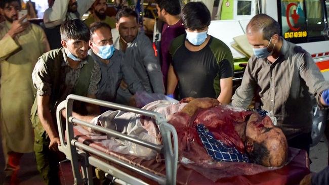 Volunteers and medical staff bring an injured man for treatment after two powerful explosions outside the airport in Kabul on Friday (AEST). Picture: AFP