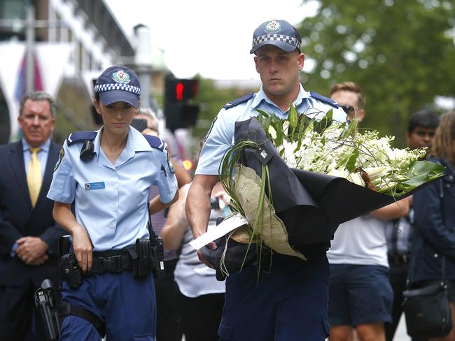 Police officers visit the flower memorial in Martin Place after the siege ended overnight. Picture: Bradley Hunter