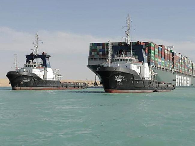 A picture released by Egypt's Suez Canal Authority on March 29, 2021, shows a tugboat pulling the Panama-flagged MV 'Ever Given' container ship after it was fully dislodged from the banks of the Suez. - The ship was refloated and the Suez Canal reopened, sparking relief almost a week after the huge container ship got stuck and blocked a major artery for global trade. Salvage crews have been working around the clock ever since the accident which has been blamed on high winds and poor visibility during a sandstorm. (Photo by - / SUEZ CANAL AUTHORITY / AFP)