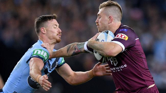 Maroons fullback Cameron Munster fends off a tackle from Blues hooker Damien Cook. Picture: AAP