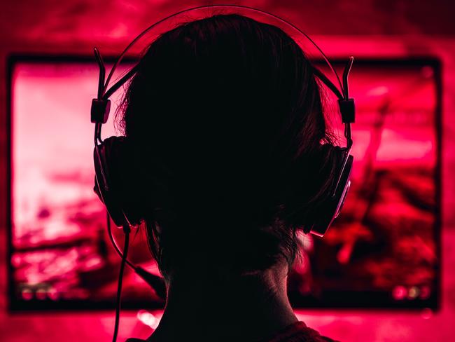 Woman wearing headphones playing video games late at night. Video games, gaming, screen time, kids and technology, headphones, generic