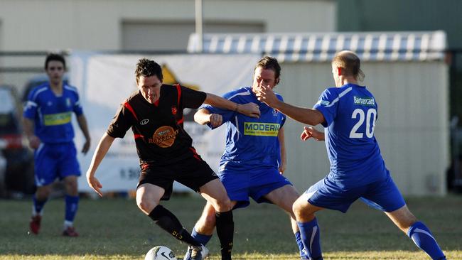 Action from the Gold Coast Premier League soccer match between Merrimac and Burleigh Heads, held at the Italo-Australian Club, Clear Island Waters. (L-R) Steve Fitzsimmons fends off James Odenbriet and Kris Dodd.