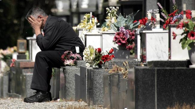 George Halvagis holds his head in his hands at a grave near where his daughter Mersina Halvagis was murdered at Fawkner Cemetery.