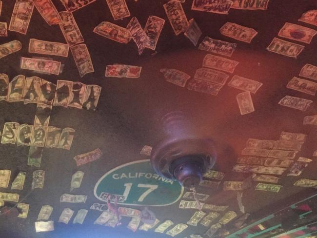 The ceiling of the rough and ready establishment is plastered with dollar bills scrawled with names and swearwords.
