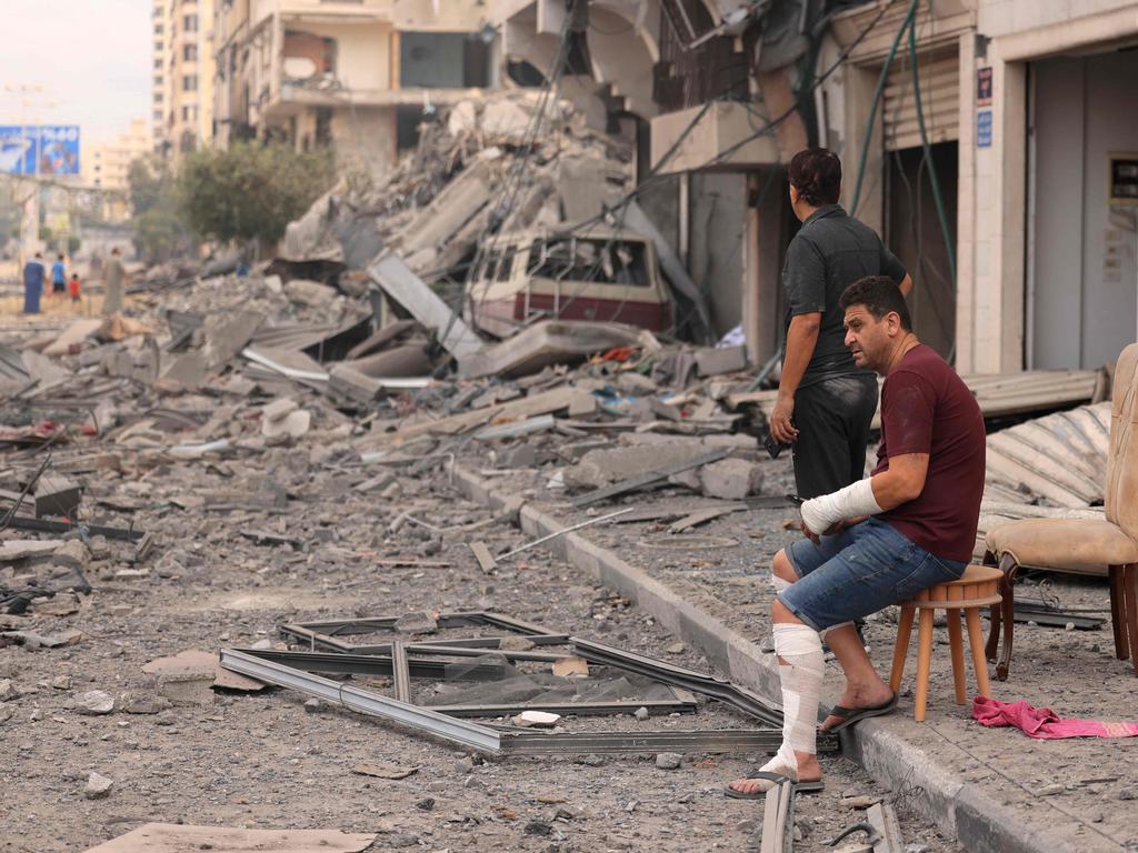 Palestinian men look at the destruction outside a damaged apartment building following Israeli air strikes on Gaza City. Picture: AFP