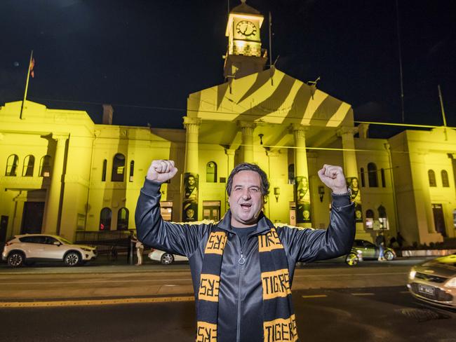 Self-confessed Tigers tragic Mick Molloy flicks the switch on a massive tiger-themed projection on Richmond Town Hall on Wednesday night. Picture: Jason Edwards