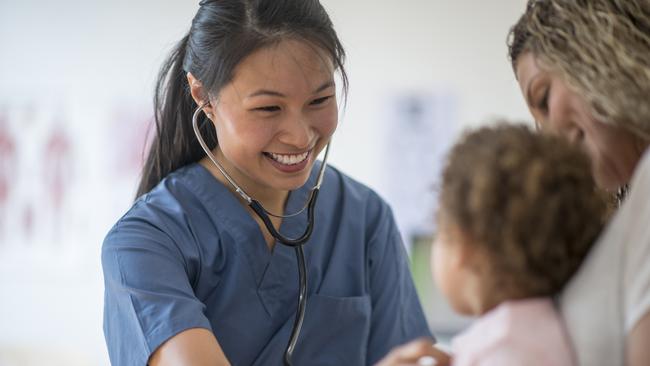 A nurse listening to a little girl's heartbeat at a doctors appointment.