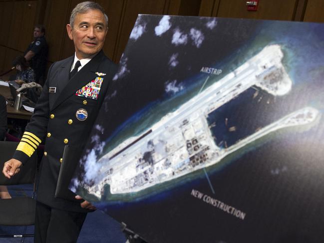 US Admiral Harry B. Harris, Jr., the now former commander of US Pacific Command, walks past a photograph showing Fiery Cross Reef. Picture: AP