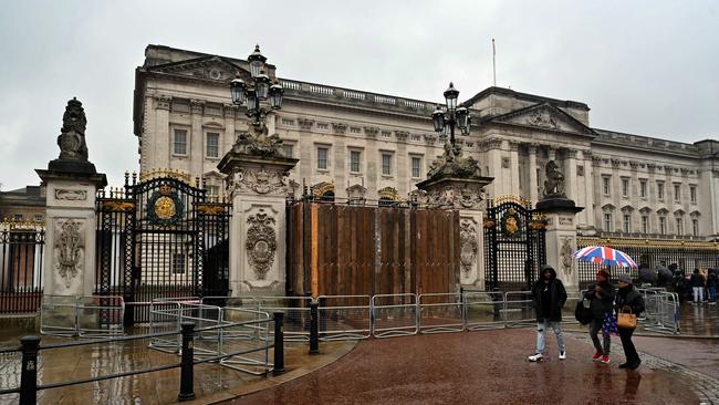 People walk past the a set of boarded up gates to Buckingham Palace in London on March 10, 2024, after a car crashed into them. Picture: AFP