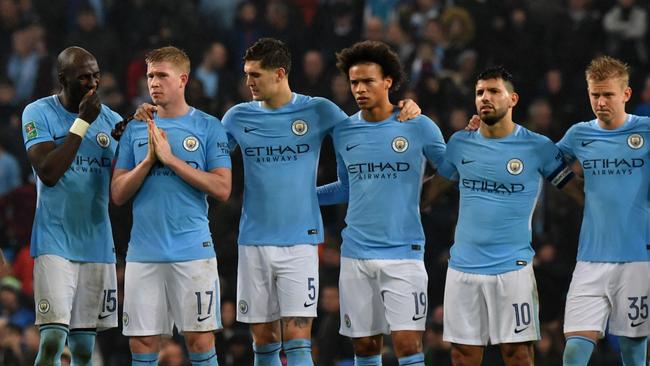 Manchester City players wait together before the penalty shoot-out