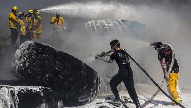 Israeli firefighters extinguish tractor tyres in a farmland set on fire by a kite with attached burning cloth launched from Gaza on the Israeli side of the border. Picture: AP