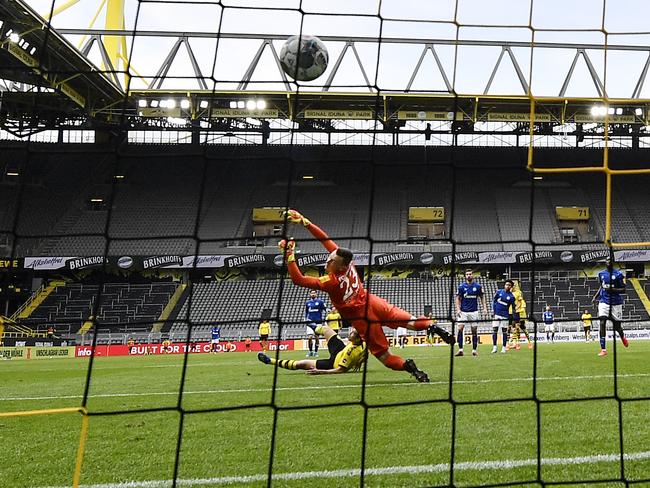 DORTMUND, GERMANY - MAY 16: Dortmund's Raphael Guerreiro scores the his side's 4th goal against Schalke's goalkeeper Markus Schubert during the Bundesliga match between Borussia Dortmund and FC Schalke 04 at Signal Iduna Park on May 16, 2020 in Dortmund, Germany. The Bundesliga and Second Bundesliga is the first professional league to resume the season after the nationwide lockdown due to the ongoing Coronavirus (COVID-19) pandemic. All matches until the end of the season will be played behind closed doors. (Photo by Martin Meissner/Pool via Getty Images)