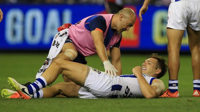 Shaun Higgins is tended to by a North Melbourne trainer. Picture: Wayne Ludbey
