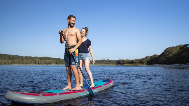 Tourists Scott and Darcie Spellacy from Tamborine Mountain paddleboard at Brown Lake on North Stradbroke Island. Picture: Lachie Millard