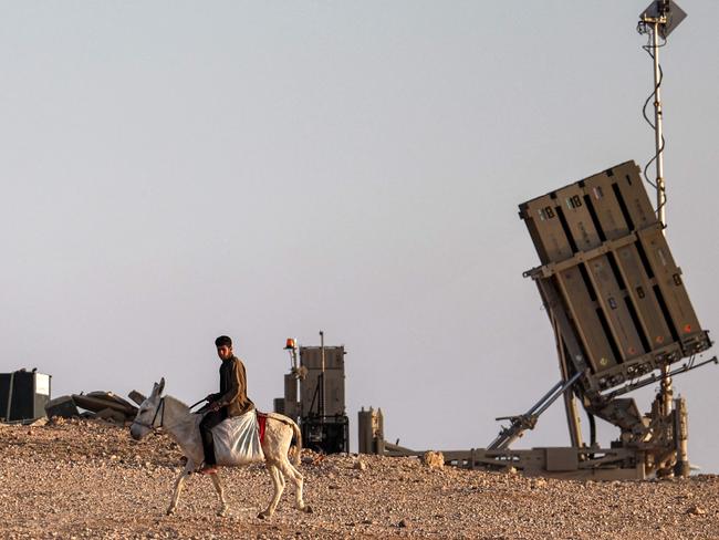 A boy rides a donkey near one of the batteries of Israel's Iron Dome missile defence system at a village not recongised by Israeli authorities in the southern Negev desert on April 14, 2024. (Photo by AHMAD GHARABLI / AFP)