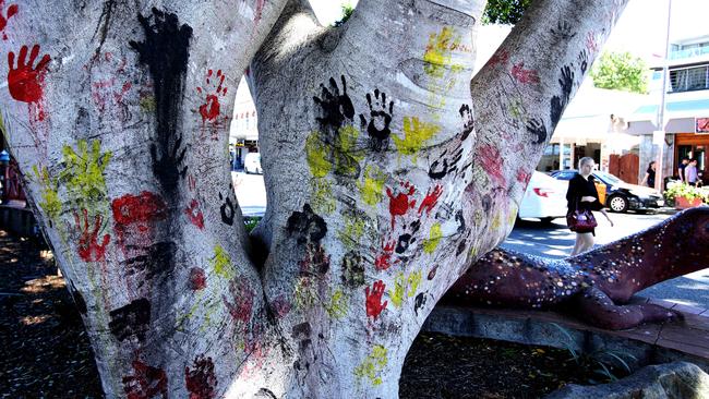 A tree on Boundary St, behind the goanna sculpture, with handprints in the colours of the Aboriginal flag. Picture: David Kelly