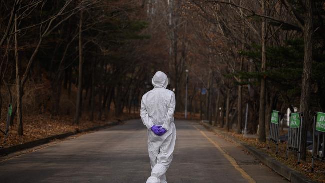 A health worker wearing a protective suit waits.