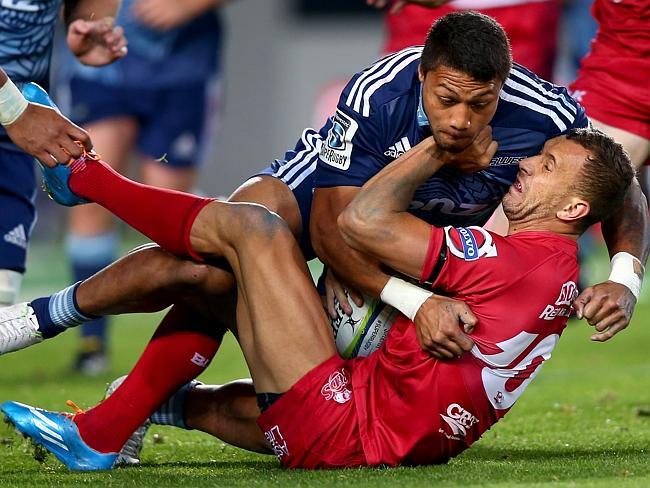 Quade Cooper of the Reds is crunched by George Moala in the Reds’ heavy loss to the Blues.