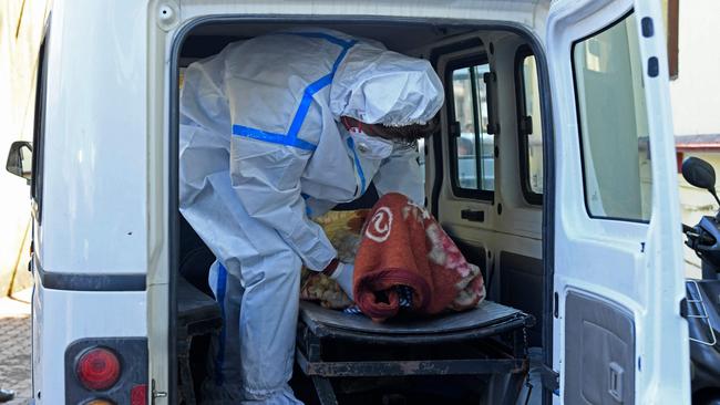 A member of medical staff wearing protective gear carries the body of a Covid victim.