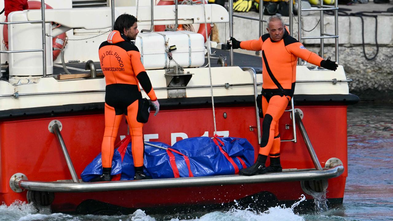 Divers with a third body at the back of the boat on Wednesday. Picture: Alberto Pizzoli/AFP)