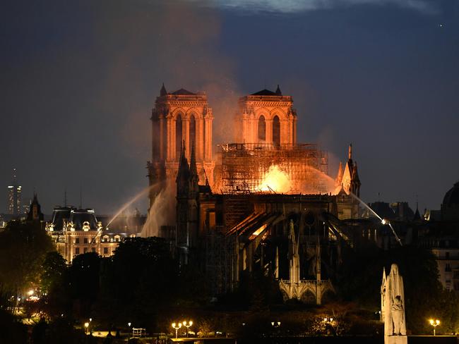Firefighters douse flames rising from the roof at Notre-Dame Cathedral in Paris on April 15, 2019. (Photo by Bertrand GUAY / AFP)